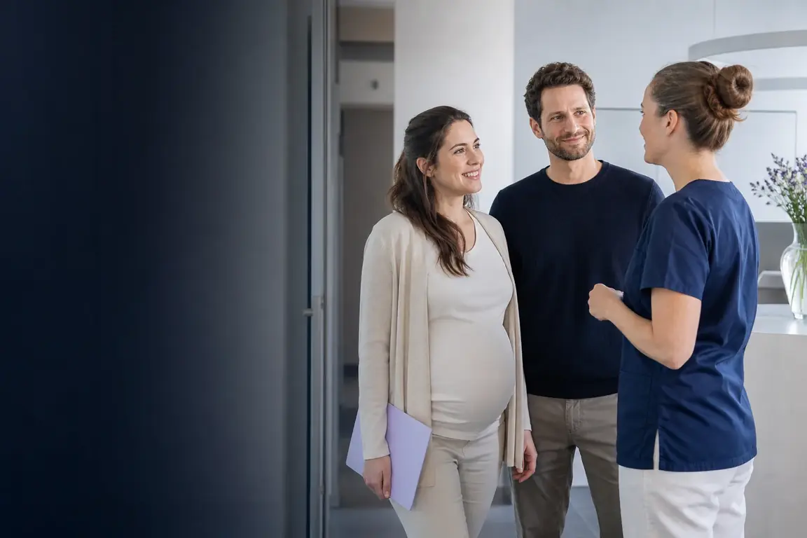 Un couple qui attend un enfant discute avec une sage-femme dans un cabinet médical