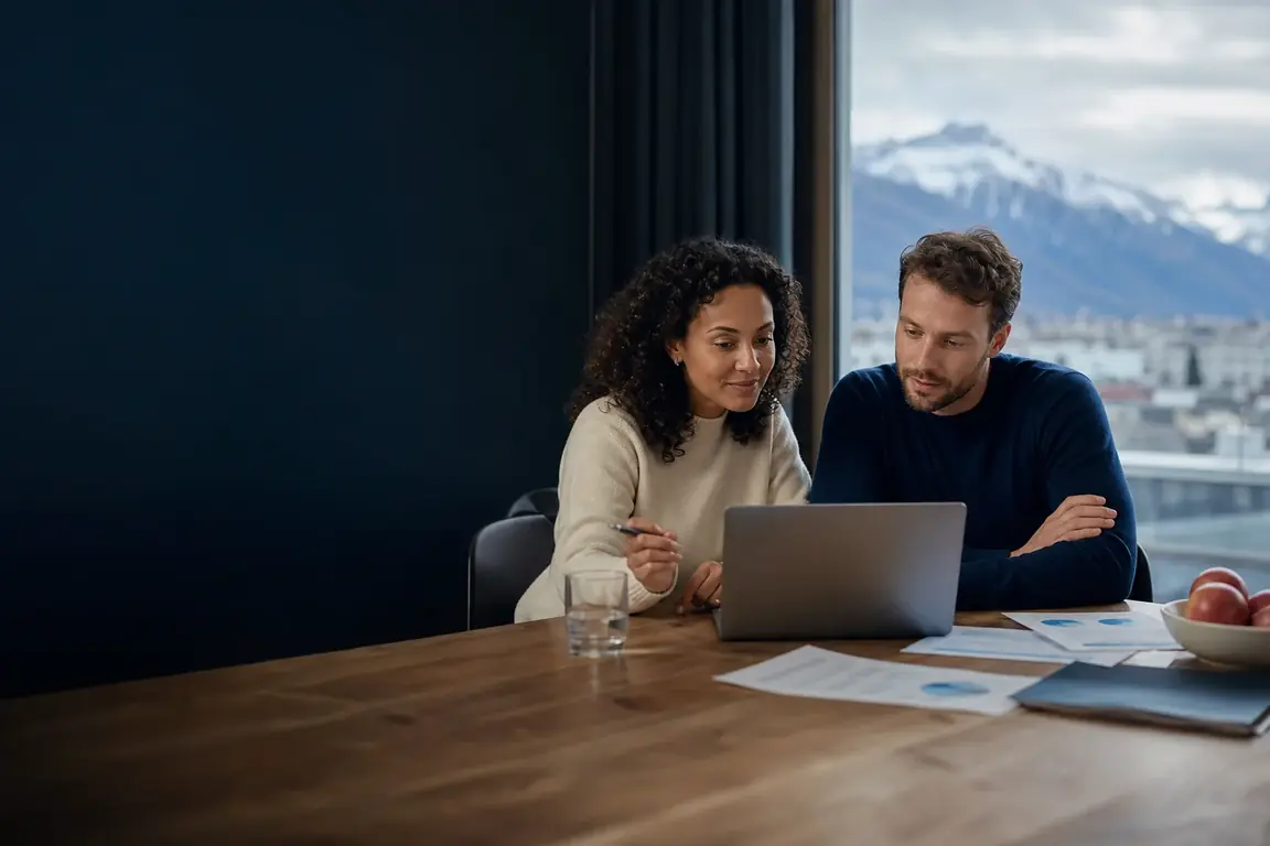 Un couple analyse les prévisions de primes 2027 sur un ordinateur portable devant une vue sur les Alpes