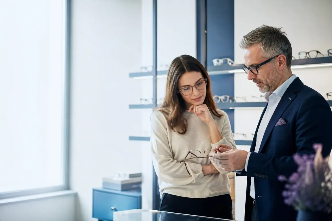 Un opticien présente une paire de lunettes à une cliente dans un magasin d'optique suisse